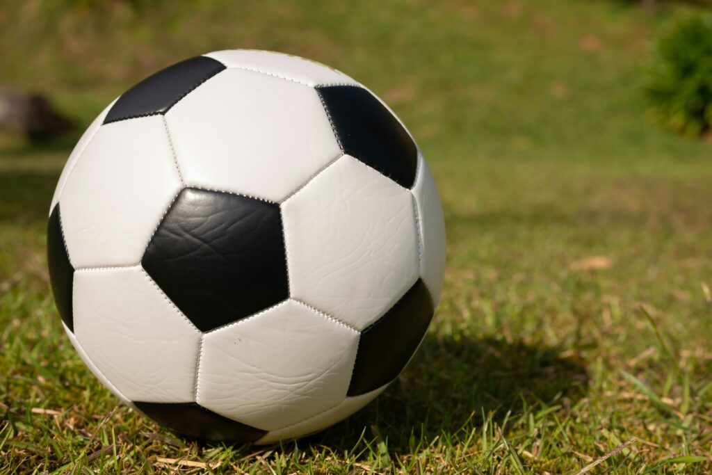 En klassisk svartvit fotboll som ligger på grönt gräs utomhus.
